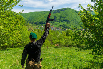Soldier in green beret overlooking and celebrating victory over a town in bright green forest...