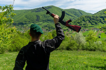 Soldier in green beret overlooking and celebrating victory over a town in bright green forest...