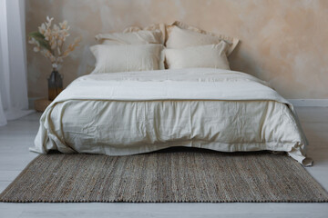 In a cozy bedroom, there is a comfortable bed adorned with crisp white sheets and fluffy pillows placed atop a stylish rug