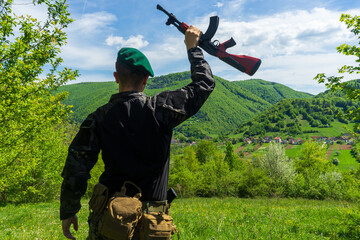 Soldier in green beret overlooking and celebrating victory over a town in bright green forest...