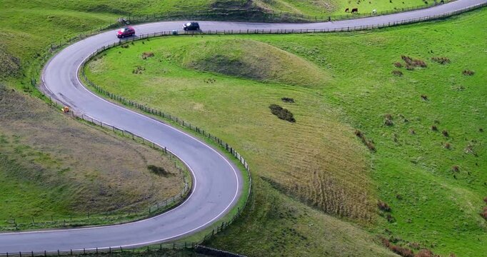Cars driving up a bendy road of the Peak District landscape in United Kingdom. 