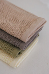 Three towels are carefully stacked, one on top of the other, resting neatly on a table surface for easy access and organization