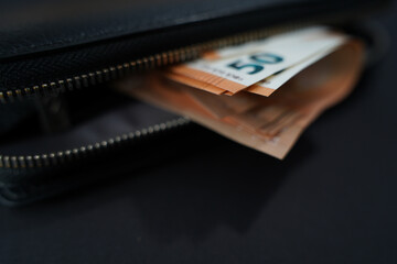 black wallet with 50 euro banknotes on black background.Finance and spending concept.