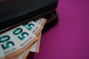 black wallet with 50 euro banknotes on pink background.Finance and spending concept.