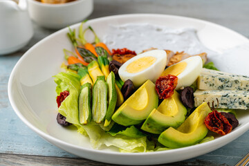 Healthy salad bowl with grilled chicken, avocado, egg, and blue cheese
