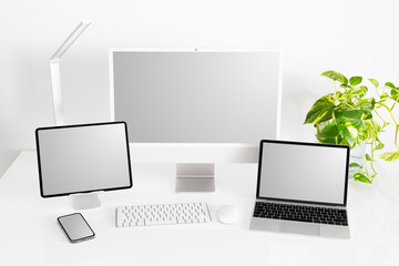 Mockup of different tech gadgets and devices on desk, laptop and desktop computers, tablet and phone