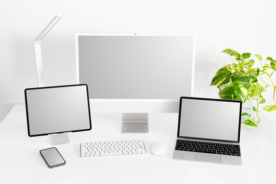 Mockup of different tech gadgets and devices on desk, laptop and desktop computers, tablet and phone