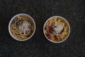 Carbonara pasta with bacon in a round cardboard takeout box
