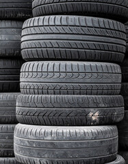 Stack of worn-out car tires. Automotive waste. Recycling and environmental impact concept.