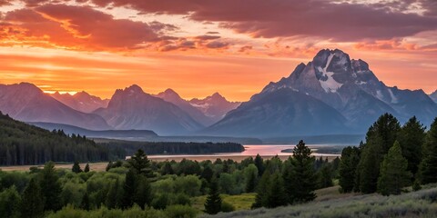 Grand teton mountains at sunset with trees and river in the foreground and orange sky above it all