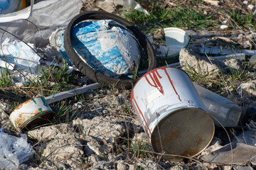 Empty old paint cans thrown away outdoors. Construction waste, trash pollutes the environment.