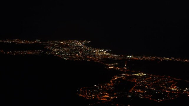 Aereal shot of Tenerife by night with city lights and traffic cars passing by filmed from a mountain top in Adeje. South Tenerife, Canary island, Spain