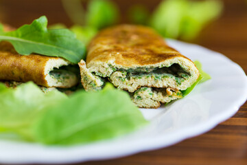 Omelette roll with greens and fresh arugula on a plate