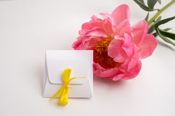 Gift box with yellow ribbon on light background with flowers and eucalyptus.