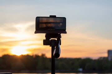 Cell phone on the tripod capturing sun set moment. Technology