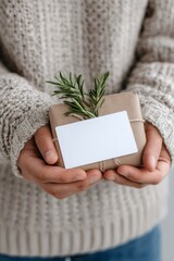 Man holding christmas gift box with rosemary decoration and blank label