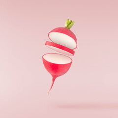 Fresh raw Red Radish with green leaves falling in the air isolated on pink backgriund. Food...