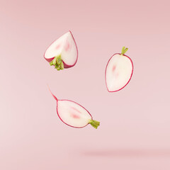 Fresh raw Red Radish with green leaves falling in the air isolated on pink backgriund. Food...
