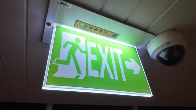Illuminated exit sign at night with CCTV. Slow motion footage.