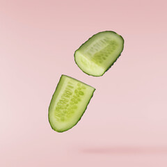 Fresh raw cucumber  falling in the air isolated on pink background. Food levitation or zero gravity...