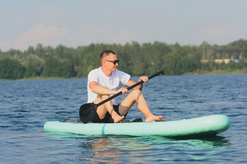 Young white man on a SUP board while relaxing on a lake