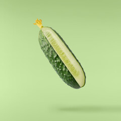Fresh raw cucumber  falling in the air isolated on green background. Food levitation or zero...