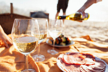 Close-up of a glass of champagne on a picnic mat. The cup is filled with sparkling wine outdoors on...