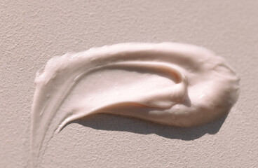 Close-up of the texture of pink cream on a light background. Moisturizing serum is smeared on the backdrop. The consistency of glycerin gel. Cosmetic smear.