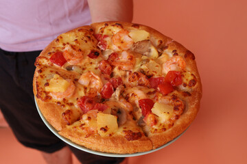 Hand holding Hawaiian pizza