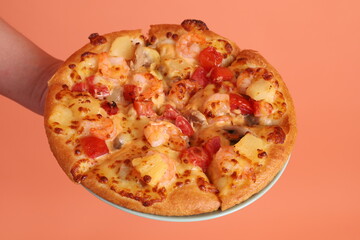 Hand holding Hawaiian pizza