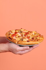 Hand holding Hawaiian pizza