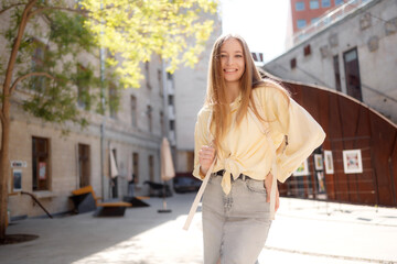 Fototapeta premium Young woman posing happily in a bright urban courtyard on a sunny day