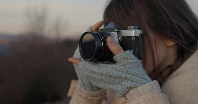 Close-up of Girl holding a camera to her face and taking a photo of mountains during her hike outside of urban areas. Nature photography outside the city