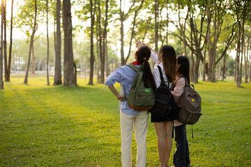 Fototapeta premium Three women are walking in a park, one of them is carrying a backpack. Scene is relaxed and casual, as the women are enjoying a leisurely walk in the park 
