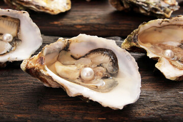 Concept, fresh sea oysters with open shells, mother-of-pearl pearls inside. Oysters on a wooden table. Seafood is rich in protein, micro and macro elements.