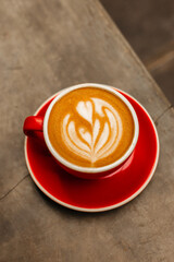 Cappuccino with nut milk in a red mug with beautiful latte art. Delicious coffee with almond milk. Cup of coffee on concrete background