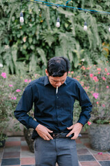 Man smoking cigarette outdoors surrounded by plants and string lights