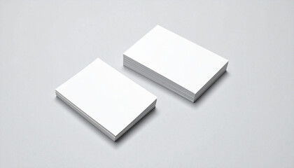 two neatly stacked stacks of white business cards resting side by side against a uniform grey background