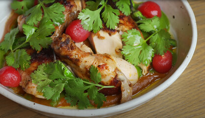 Grilled chicken Piri Piri served in a bowl with vibrant cilantro leaves and cherry tomatoes in a rich sauce, captured in a flavorful and rustic presentation.