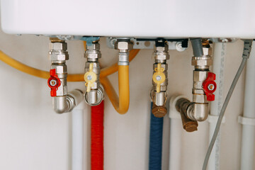 Close-up view of water heater pipes and valves in a utility room, featuring colorful connectors and...