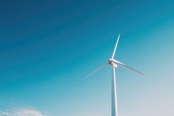 Obraz premium lone wind turbine standing tall against cloudless blue sky its blades catching gentle sunlight representing renewable