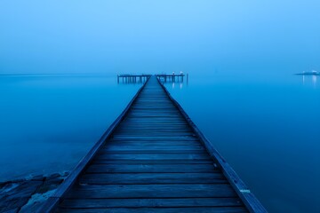 Fototapeta premium Serene Wooden Pier Stretching into Misty Blue Waters at Dusk