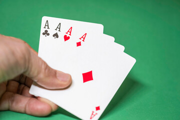 Hand showing four aces cards on a green background.