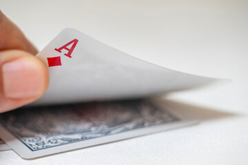 Close-up of a hand raising an ace of diamonds card