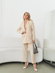 Chic model in elegant cream suit poses confidently in modern studio environment