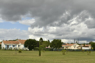 Gros nuages gris au dessus d'un lotissement résidentiel au bourg de Champagne au Périgord Vert  © Photocolorsteph