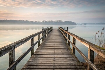 Fototapeta premium Serene Wooden Dock Extending into Misty Lake Landscape at Dawn