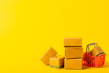 Online shopping concept.Cardboard box and shopping bags in a trolley on a bright colored background. Shopping basket. Online shopping using a laptop, tablet, phone and credit card. Home delivery.