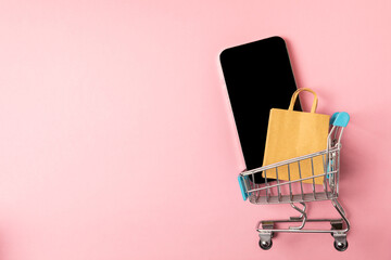 Online shopping concept.Cardboard box and shopping bags in a trolley on a bright colored...