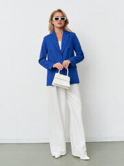 Captivating woman in bold blue blazer showcases modern fashion in studio setting